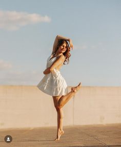 a young woman is dancing on the street with her arms behind her head and legs in the air