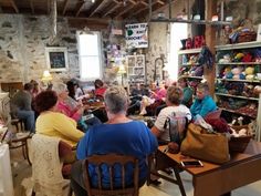 a group of people sitting around tables in a room with many items on the shelves