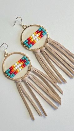 Beautiful handmade boho, hippy, cowgirl native themed statement earrings. Hand beaded, knotted and created by me.  These earrings are approximately 4.5 inches in total length. They are lightweight considering their size. They feature Turquoise, Red, Orange, Yellow and White beading on gold hardware. Sleek and trendy circle shape, with Beige soft suede leather fringe. Very eye catching on the ear. Definitely consider these babies as statement pieces.  Perfect for rodeo, festival and concert season! Would pair perfectly with a hat and boots, a tee and jeans, or even sandals and your favorite maxi dress! Bohemian Adjustable Beaded Earrings With Large Beads, Adjustable Southwestern Beaded Earrings For Beach, Handmade Heishi Beads Earrings For Festivals, Bohemian Heishi Beaded Hoop Earrings, Bohemian Hoop Beaded Earrings With Heishi Beads, Bohemian Hoop Beaded Earrings With Colorful Beads, Bohemian Brown Heishi Beads Jewelry, Bohemian Hoop Earrings With Heishi Beads, Nickel-free Bohemian Beaded Earrings For Crafting