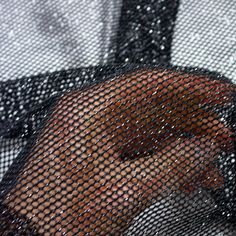 a close up of a person's hand through a mesh screen