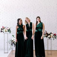 three bridesmaids in green dresses standing next to each other on a wooden floor