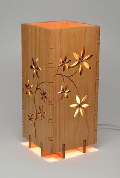 a wooden box with flowers on it is lit up by a small light bulb that's plugged in