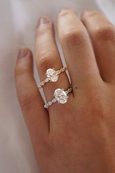 a woman's hand with two diamond rings on top of her finger and the other ring