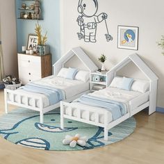 two beds in a room with blue walls and wooden flooring, one is white and the other is light blue