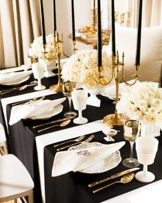 the table is set with black and white linens, gold place settings, and flowers