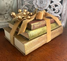 three books stacked on top of each other with a ribbon tied around the book ends