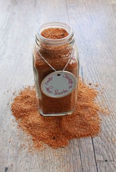 a jar filled with red sand sitting on top of a wooden table next to a tag