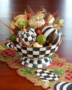 a decorative bowl filled with gourds and squash on top of a wooden table