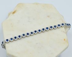 Absolutely incredible 925 Sterling Silver tennis bracelet with 23 total pieces, a stunning royal blue centre stone, surrounded by nine cubic zirconia stones. This bracelet is stylish, sparkly and made to look like real diamonds and sapphires. It's design will really turn heads and is ideal for a special occasion such as a wedding or event. - Bracelet Size: 17.5cm long - Bracelet Width: 6.5mm - Bracelet closure: secure clasp - Hallmarked 925 for solid sterling silver. Looking for a gift for your team of bridesmaids? We offer a discount if purchasing more than three cubic zirconia silver bracelet - send us a message and we'll be happy to help! Sapphire Cubic Zirconia Bracelets, Sapphire Color Cubic Zirconia Diamond Bracelet Gift, Sapphire Cubic Zirconia Tennis Bracelet, Sapphire Cubic Zirconia Tennis Bracelet With Gemstone, Sapphire Cubic Zirconia Diamond Bracelet For Anniversary, Sapphire Color Brilliant-cut Cubic Zirconia Bracelets, Anniversary Sapphire Diamond Bracelet In Cubic Zirconia, Sapphire Tennis Bracelet With Diamond Accents, Sapphire Diamond Tennis Bracelet Gift