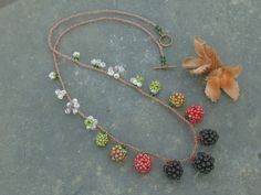 a necklace with beads and flowers on it sitting next to a small flower potted plant