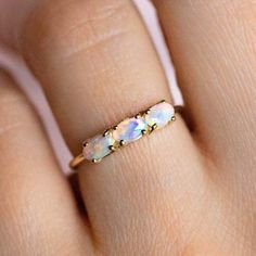 a woman's hand with an opal ring on top of her finger,