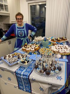 a woman standing next to a table filled with desserts