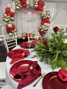 the table is set with red plates, silverware and balloons in the shape of a wreath