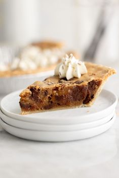 a slice of pie with whipped cream on top sits on a plate next to another piece of pie