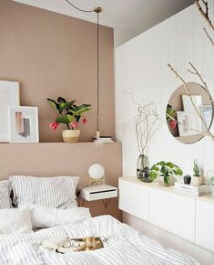 a bed with white sheets and pillows in a bedroom next to two mirrors on the wall