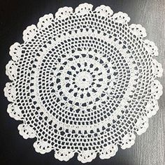 a white doily is sitting on a black tablecloth with an oval design in the center