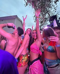 a group of young women standing next to each other at a party in bikinis