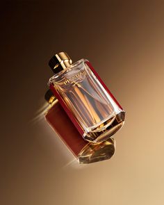 a bottle of perfume sitting on top of a red box with gold trimmings