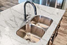 a kitchen with marble counter tops and stainless steel sink faucets in the center