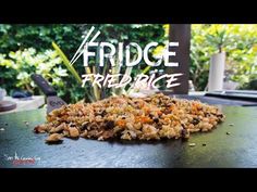 a pile of fried rice sitting on top of a wooden table next to trees and bushes