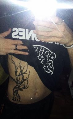 a person with tattoos on their stomach taking a selfie in front of a mirror