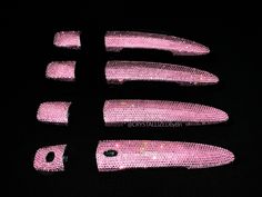 four pink knives are laying on the black surface, with holes in each one that have been sequined onto them