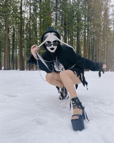 a woman in black and white makeup is sitting in the snow