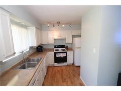 an empty kitchen with white cabinets and wood flooring is seen in this image from the doorway