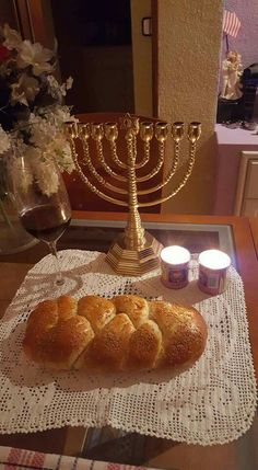 a table topped with bread and candles next to a menorah