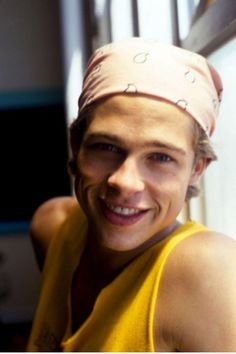 black and white photograph of a smiling man wearing a paper hat on top of his head