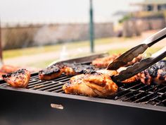 someone is grilling chicken on the grill with tongs