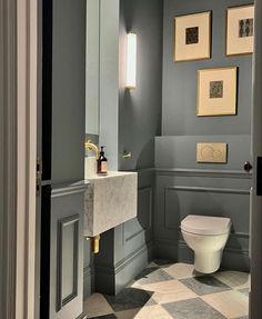 a white toilet sitting in a bathroom next to a wall mounted light above it's tank