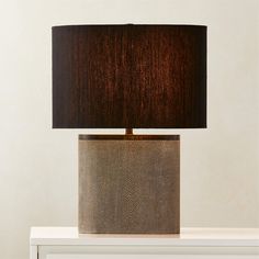 a lamp that is sitting on top of a white table with a brown shade over it