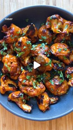 chicken wings with parsley in a blue bowl on a wooden table top, ready to be eaten