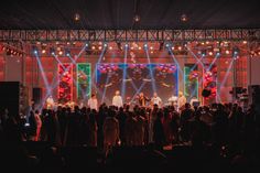 a group of people standing on top of a stage with lights in front of them