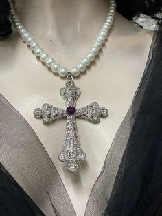 Large filigree cross pendant pearl chain. Cross has clear rhinestone, and red Swarovski crystal in the center. I have used three sizes white pears for the chain 10 mm , 8 mm and 6 mm glass pearls. Cross is zinc alloy. The Centre purple stone is 8mm Swarovski crystal colour Amethyst I can do any colour pearls to suit you. White Crystal Cross Necklaces, Pearl Cross Necklace With Pearl Chain, Elegant Silver Cross Pearl Necklace, Elegant Crucifix Pearl Pendant Necklace, Elegant Crucifix Necklace With Pearl Pendant, Silver Cross Necklace With Pearl Chain, Elegant Pearl Crucifix Necklace, Elegant Cross Necklace With Pearl Drop, Silver Cross Pendant Necklace With Pearl Chain