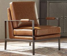 a brown leather chair sitting on top of a rug next to a metal cabinet and lamp