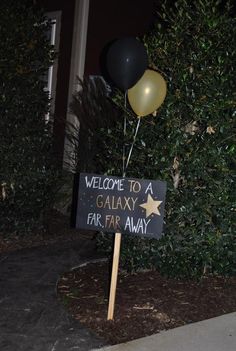 a welcome to galaxy sign with balloons in the shape of stars and a star on it