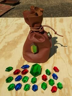 the bag is full of colorful glass pieces on top of a wooden table next to it's drawstring