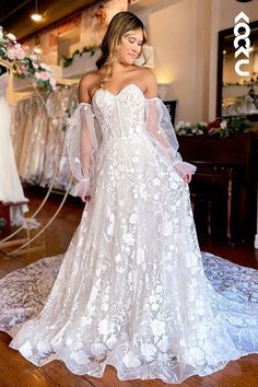 a woman in a white wedding dress standing on a wooden floor with her arms behind her back