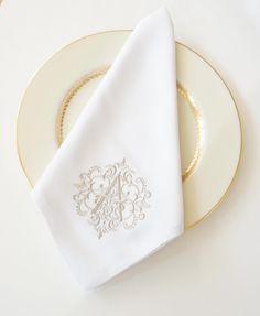 a white plate topped with a napkin next to a gold and white dinnerware set on top of a table