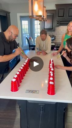 a group of people standing around a table with red cups on it and one person holding a toothbrush