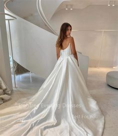 a woman in a white wedding dress standing next to a spiral stair case and looking at the camera