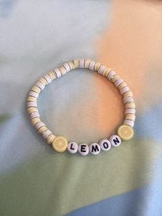 a beaded bracelet with lemons and the word lemon on it is sitting on top of a bed