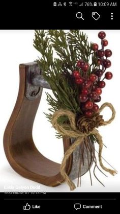 a vase filled with red berries and greenery on top of a wooden stand next to a pine cone