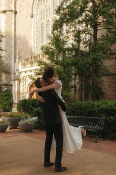 a bride and groom hugging in front of a church