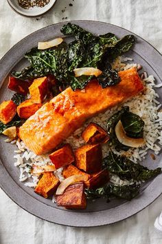 a plate with salmon, rice and greens on it