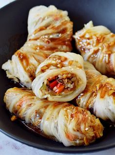 some food is in a black bowl on a table and it looks like they have been rolled up