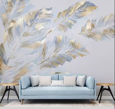 a blue couch sitting in front of a wall with gold feathers on it's side