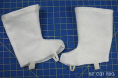 two pairs of white boots sitting on top of a blue cutting mat next to each other